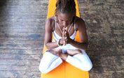 Woman meditating in lotus pose on an orange Liforme Yoga Mat