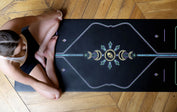Woman sitting cross-legged on a black Liforme Yoga mat