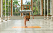 Handstand split on an orange Liforme yoga mat for advanced yoga