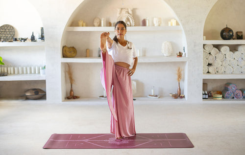 Standing Hand to Big Toe Pose on a Maroon Liforme Yoga Mat with one leg extended forward to stretch hamstrings and improve balance