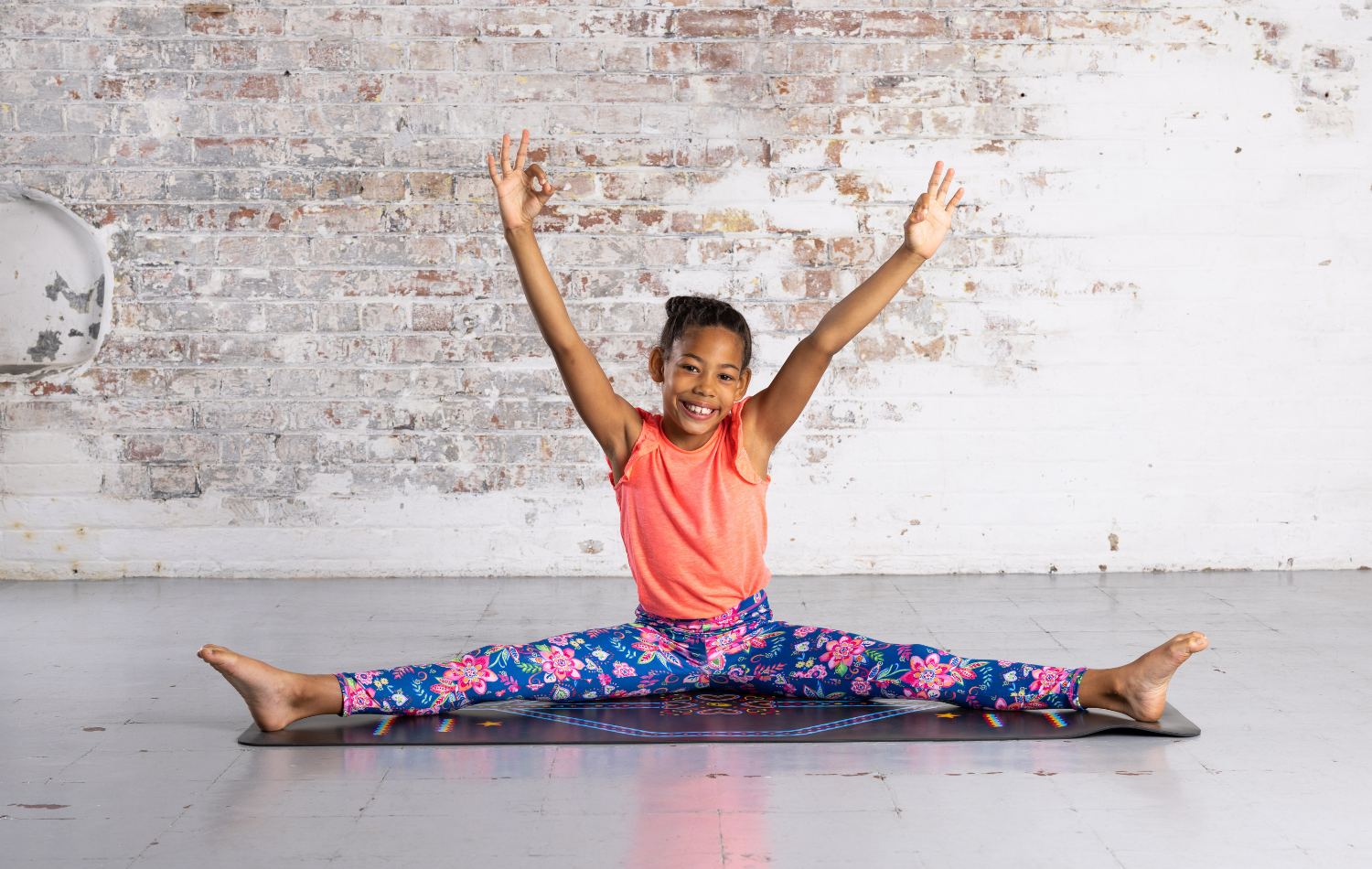Child in Wide Angle Pose on a Black Liforme Kids Yoga Mat