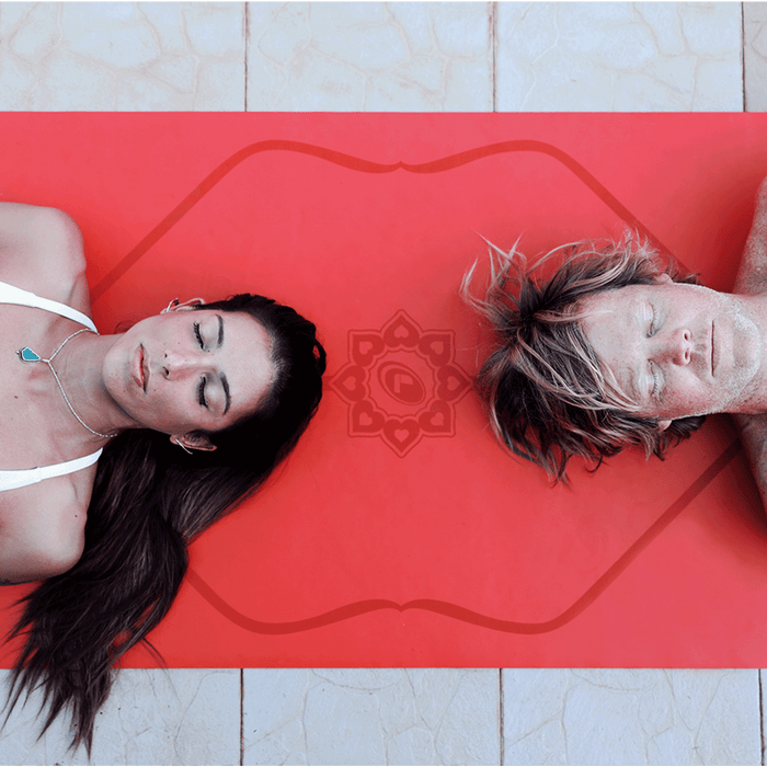 Top-down view of two people laying on a Liforme Expressions Love Red Yoga Mat