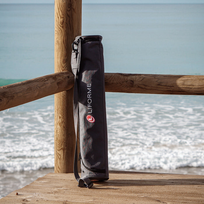 Liforme yoga mat bag leaning against a wooden railing with ocean in the background