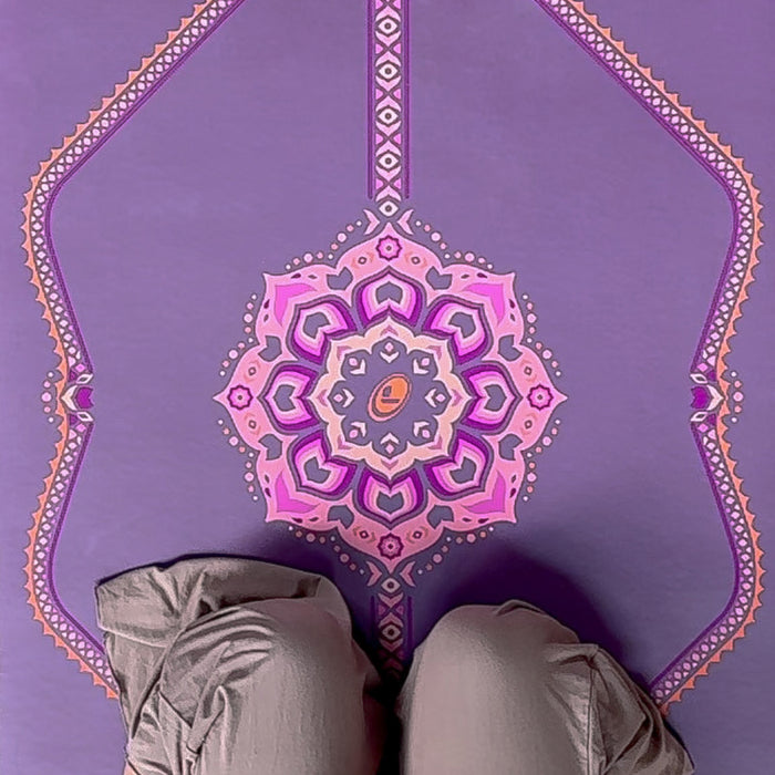 A top-down view of a woman meditating on a Liforme Blossoming Lotus Purple yoga mat.