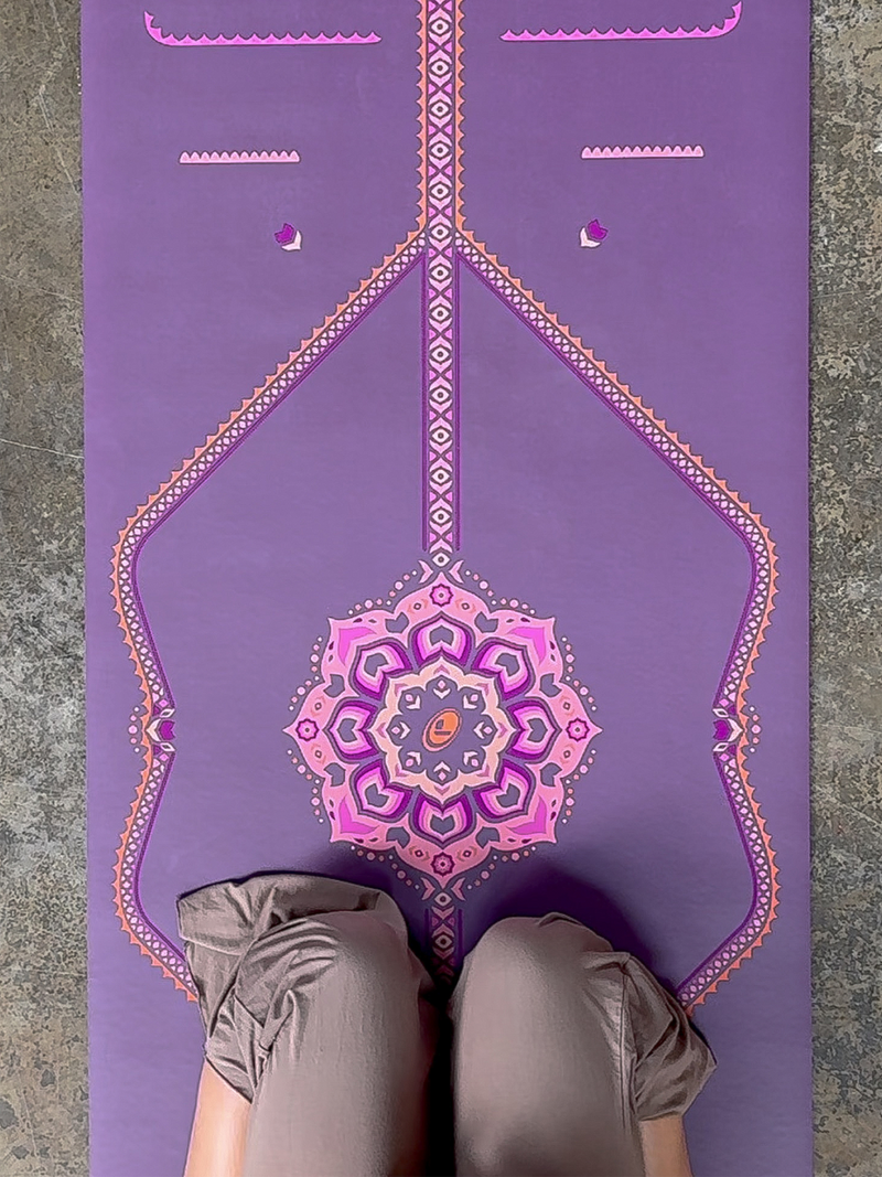 A top-down view of a woman meditating on a Liforme Blossoming Lotus Purple yoga mat.