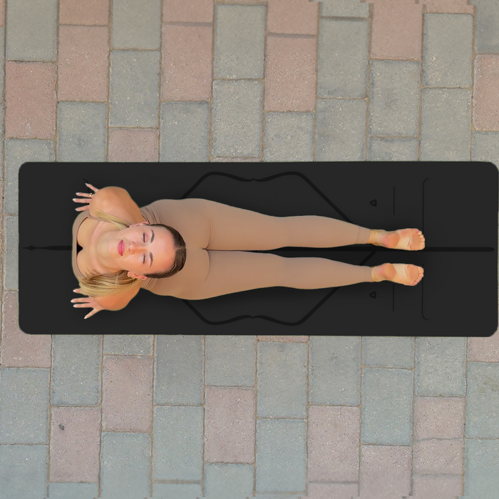 Yogi performing a cobra pose on the black Liforme Classic Yoga on a stone pavemet