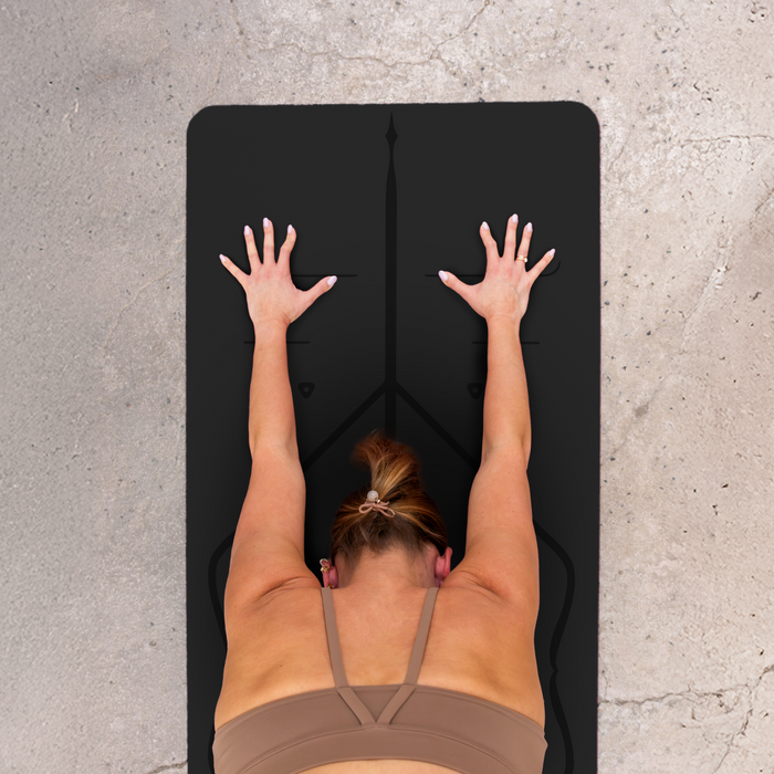 Yogi practicing yoga on a black mat with a concrete floor background
