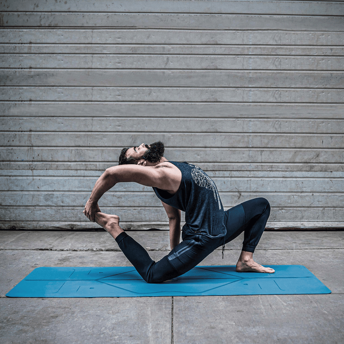 Man practicing a King Pigeon lunge variation (Eka Pada Rajakapotasana) on a blue Liforme Classic Yoga Mat.