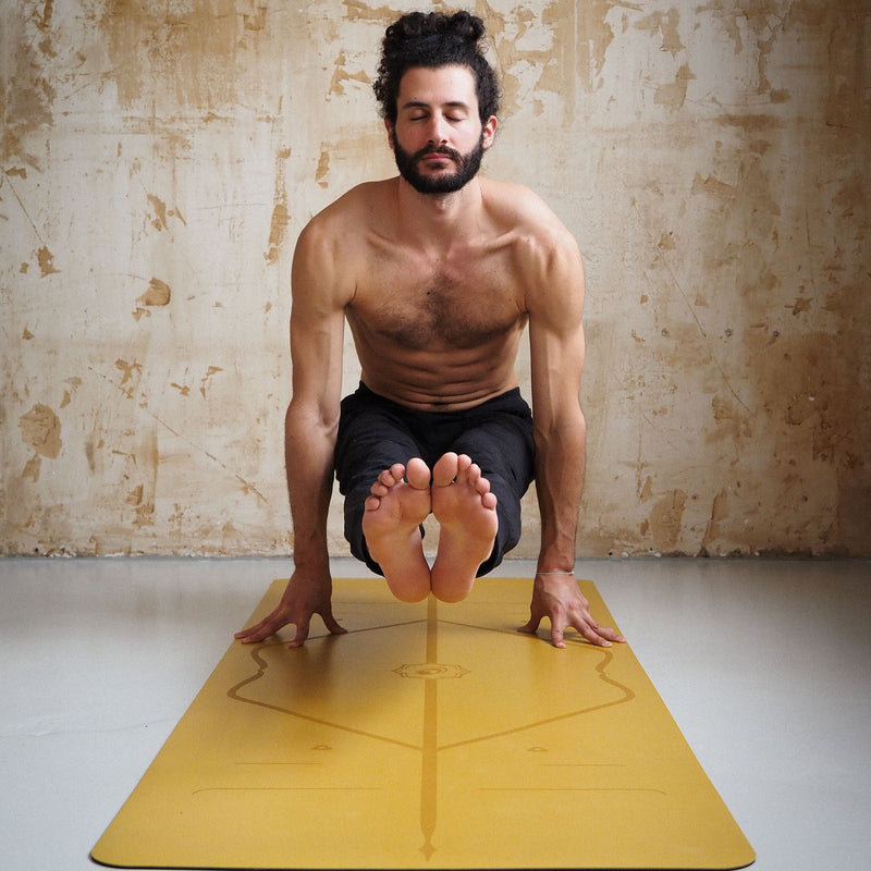 Man performing the Firefly Pose (Tittibhasana) arm balance on a golden sand Liforme Classic Yoga Mat.