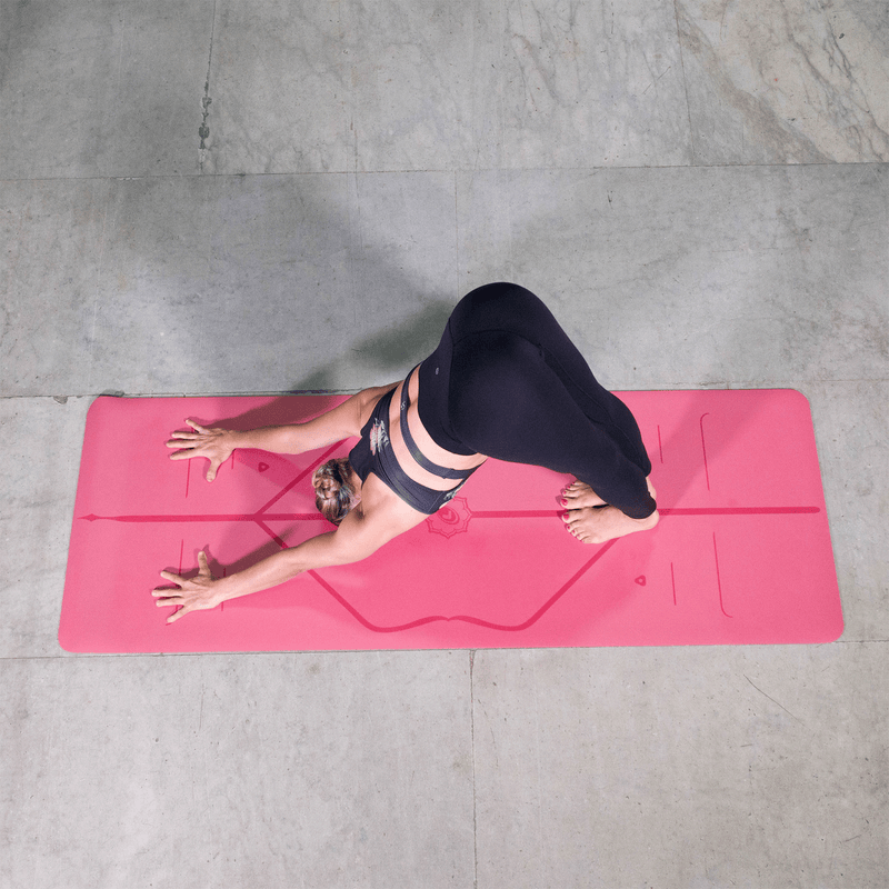 Overhead view of a woman performing Downward-Facing Dog (Adho Mukha Svanasana) on a pink Liforme Classic Yoga Mat.