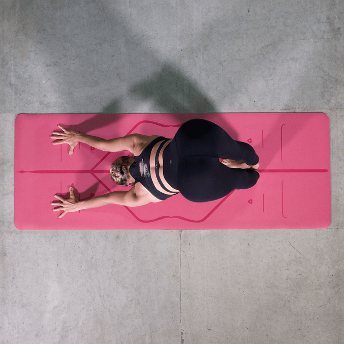 Overhead view of a woman performing Downward-Facing Dog (Adho Mukha Svanasana) on a pink Liforme Classic Yoga Mat.