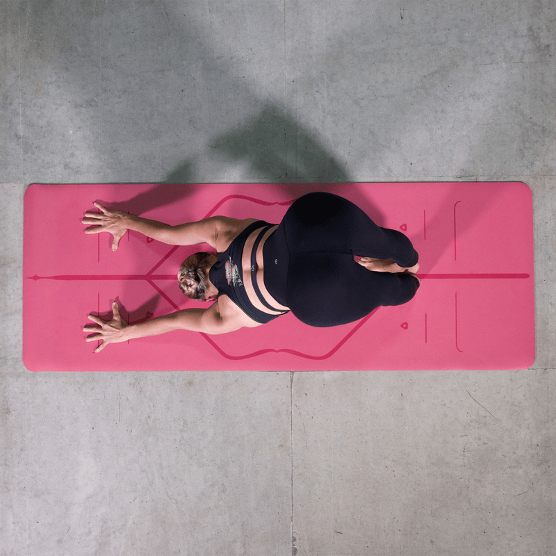 Overhead view of a woman performing Downward-Facing Dog (Adho Mukha Svanasana) on a pink Liforme Classic Yoga Mat.
