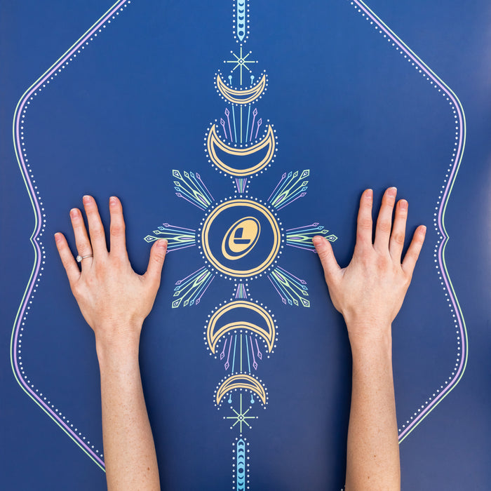 Hands on a blue Yoga mat with a celestrial moon design