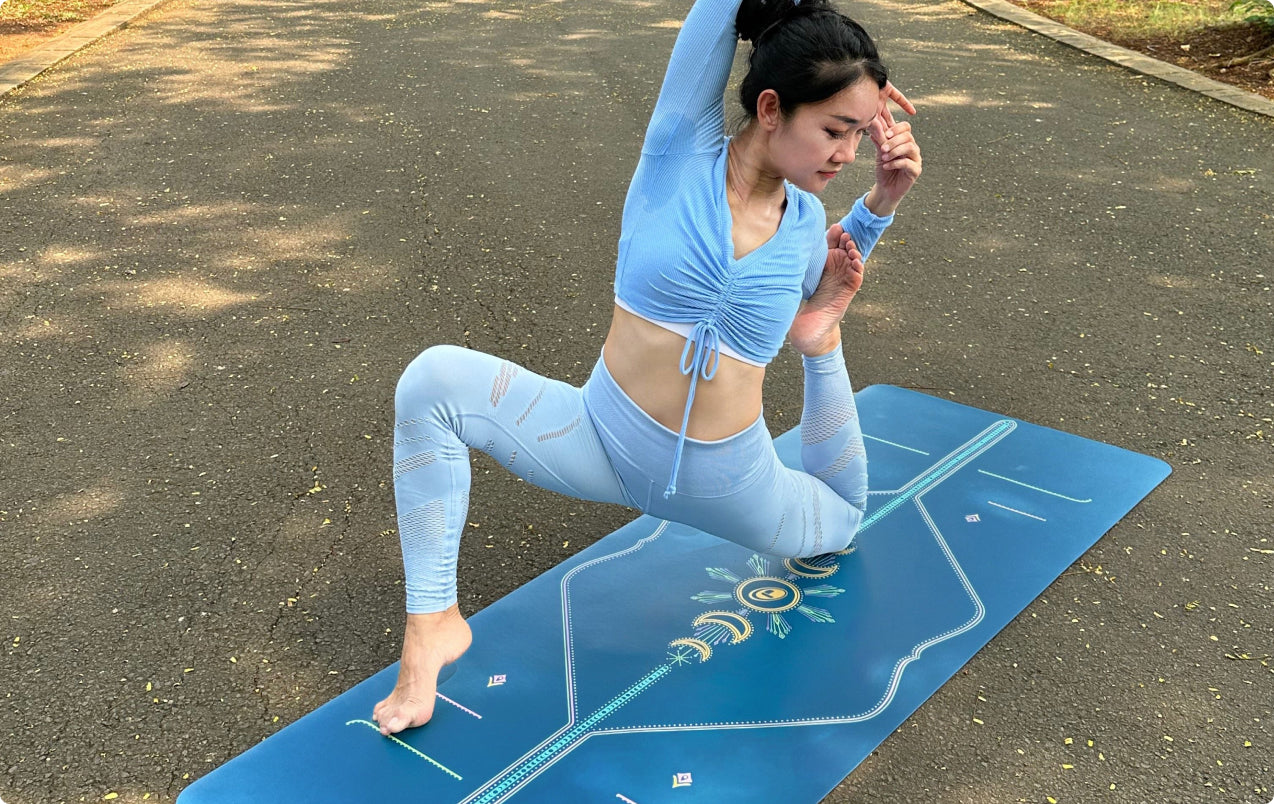 A yogi practicing a kneeling pose on the Dusk Blue Cosmic Moon Yoga Mat outdoors, that provides joint support and stability on a hard outdoor surface.