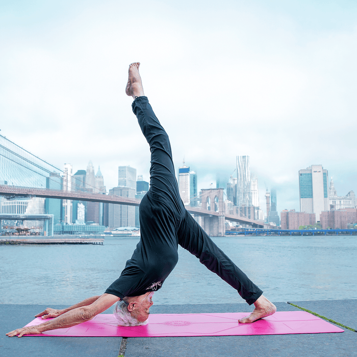 A man performing a One-Legged Downward Dog Pose on a Liforme Gratitude Pink Yoga Mat