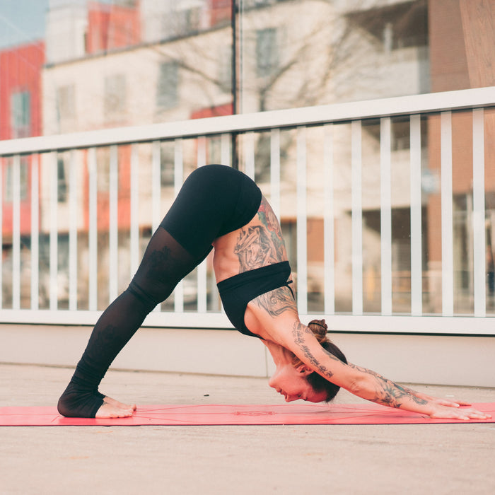 A person practicing a downward-facing dog on a Liforme Expressions Love Red Yoga Mat