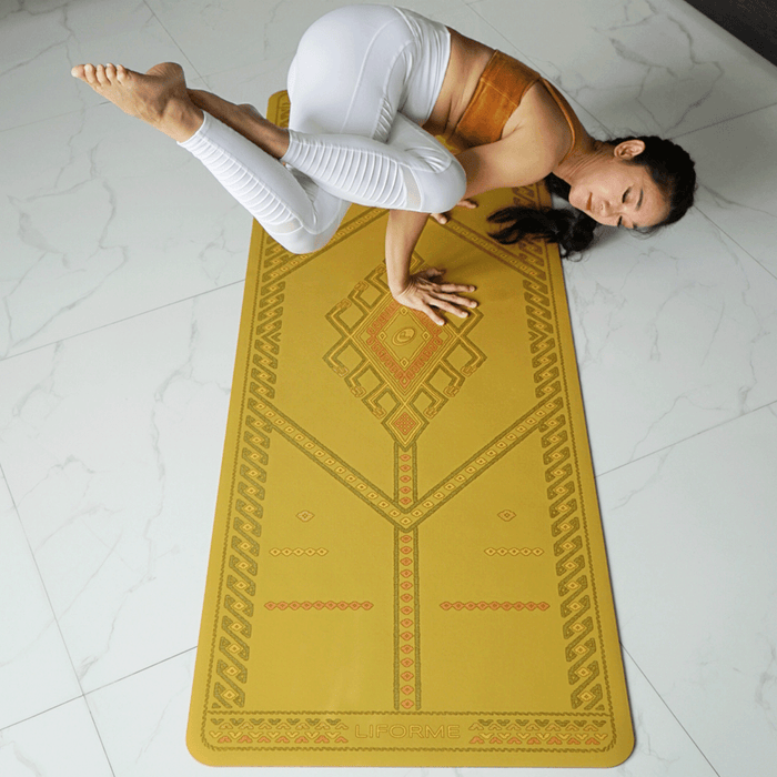 A woman performs a yoga pose on a  Liforme Majestic Carpet Golden Sand yoga mat 