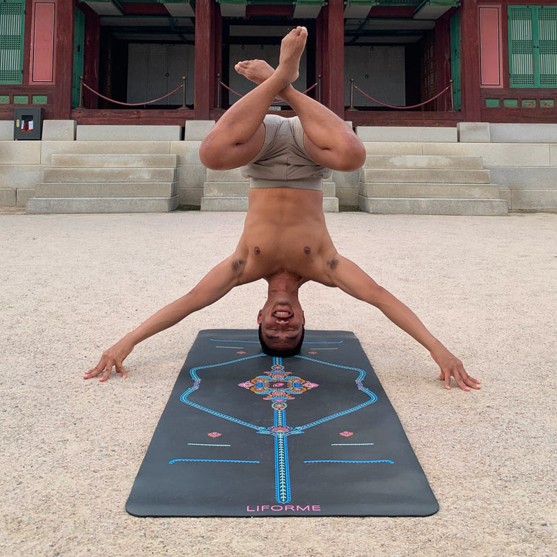 Man practicing a lotus headstand on a grey Liforme Mindful Garden Mat at a traditional outdoor temple.