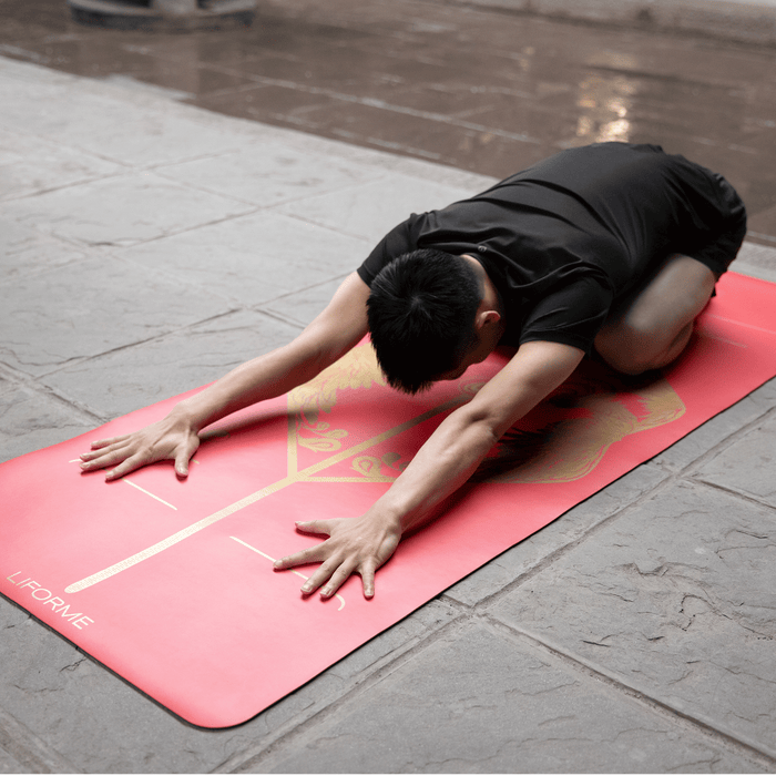 A man practicing a child yoga pose on a Liforme Phoenix Yoga Mat 