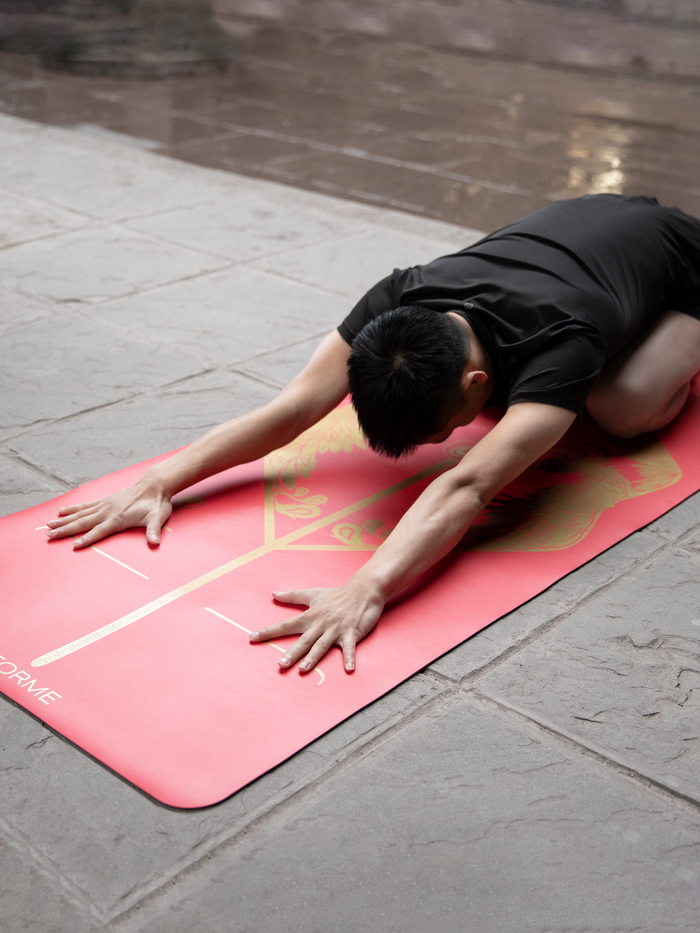 A man practicing a child yoga pose on a Liforme Phoenix Yoga Mat 