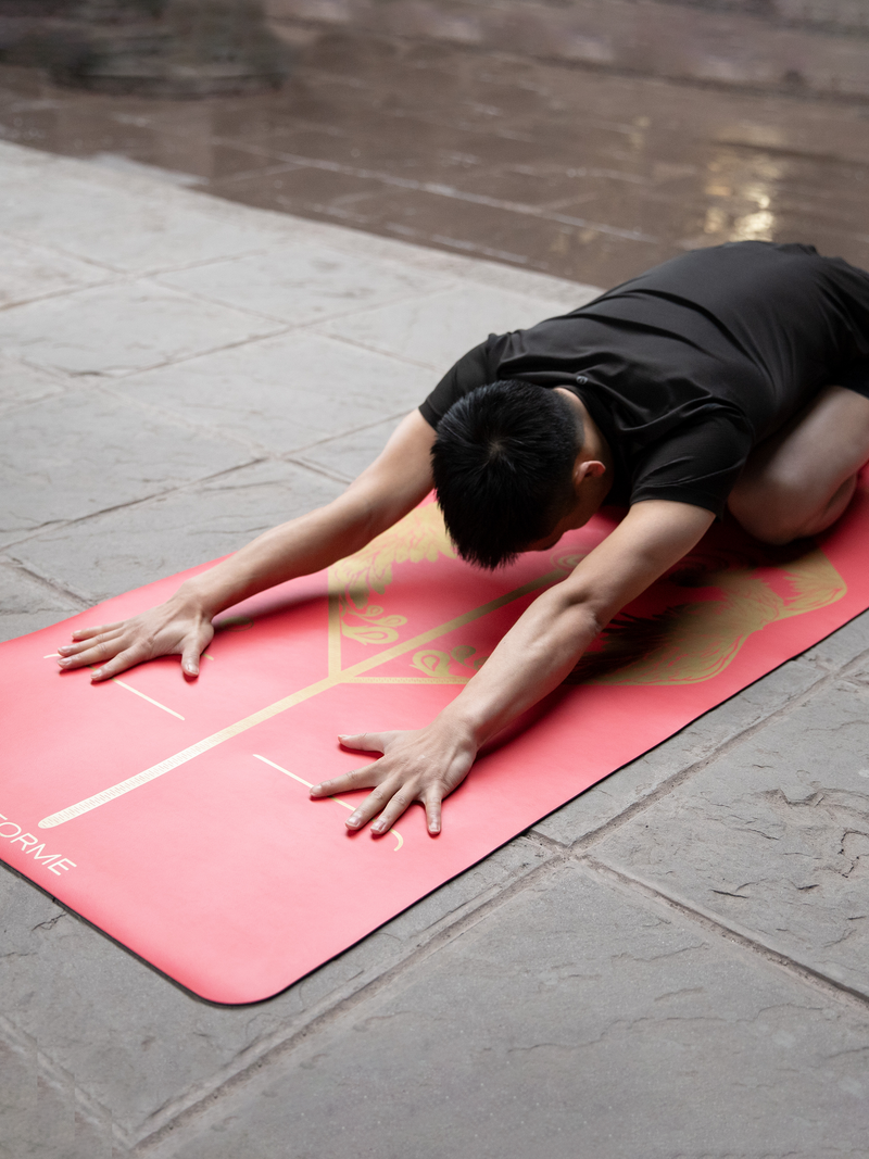 A man practicing a child yoga pose on a Liforme Phoenix Yoga Mat 