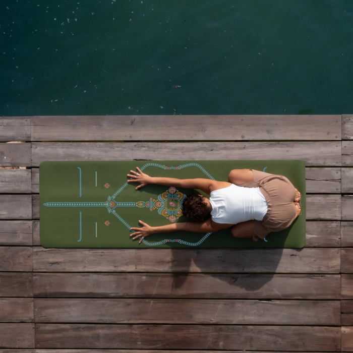 Overhead view of a Yogi in Child’s Pose on an Olive Green Liforme Mindful Garden Yoga mat, practicing on a wooden dock by the water to demonstrate the mat's grip and alignment system.