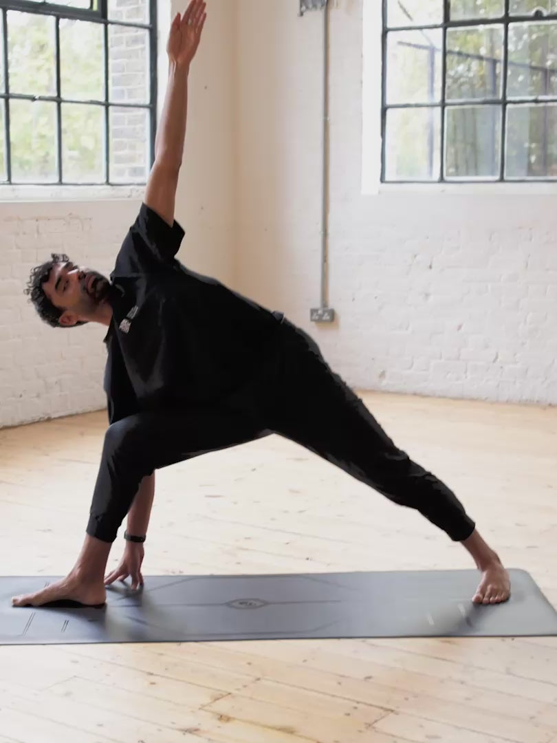 A man practice yoga on a Liforme In Line Black Yoga Mat in a bright yoga studio.