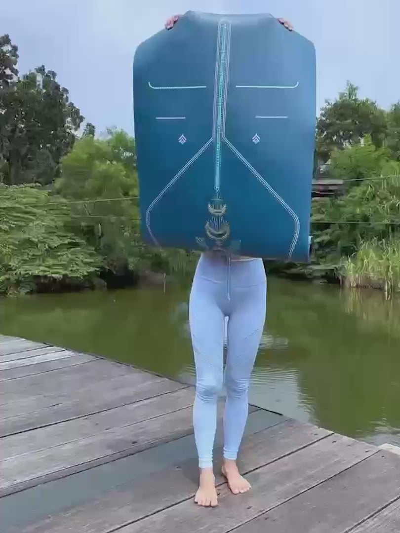 A woman performs a yoga pose on a Liforme Cosmic Moon Blue yoga mat outdoors.