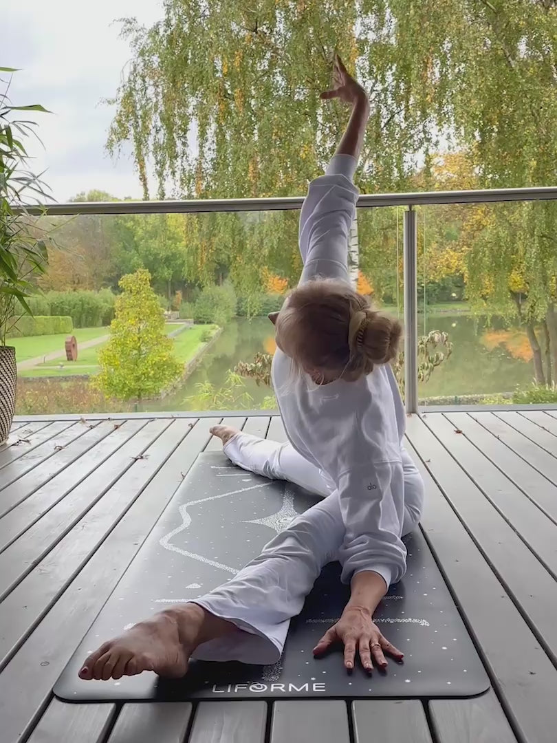 A woman performing yoga on a Liforme Magic Galaxy Yoga Mat Silver Black
